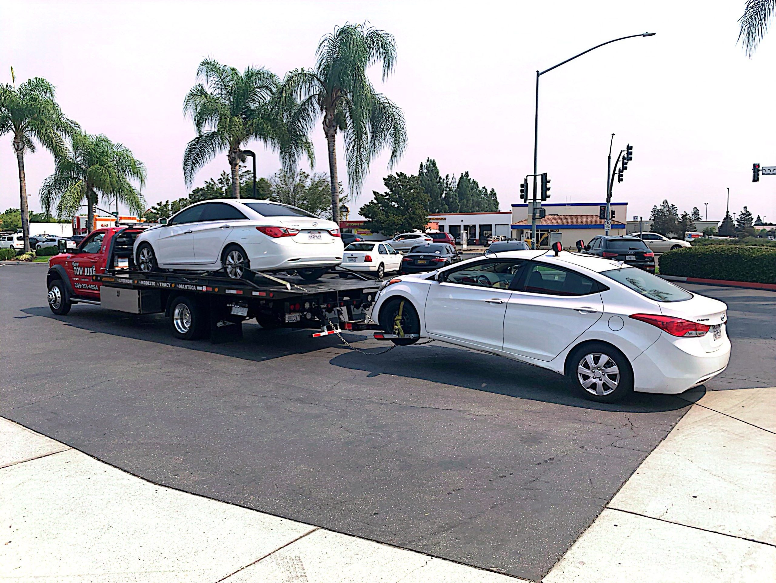 Tracy Tow King with two white sedans being towed
